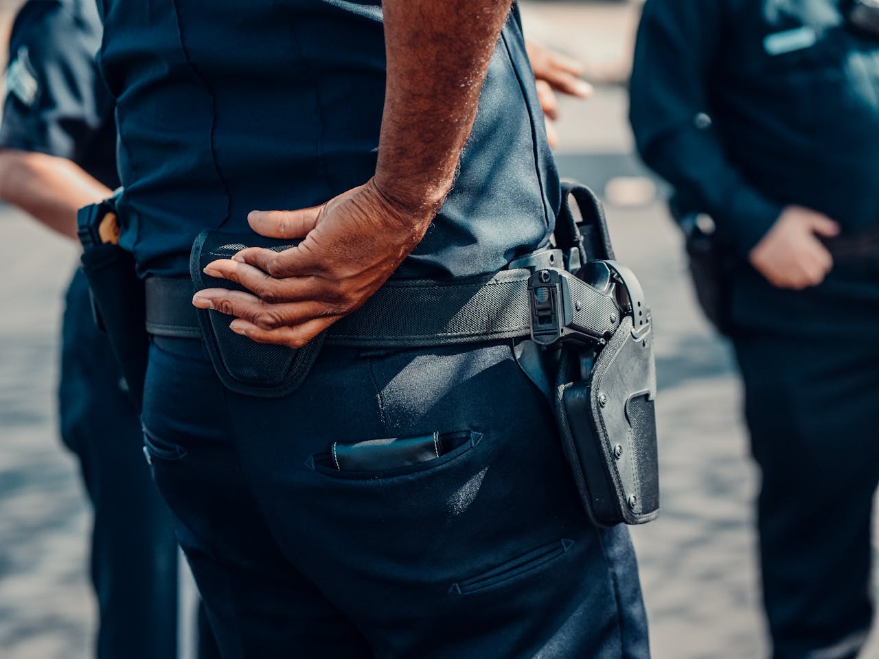 Close-up view of a police officer in uniform with a focus on the holster and handgun.